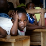 boy in white shirt sitting on brown wooden desk chair